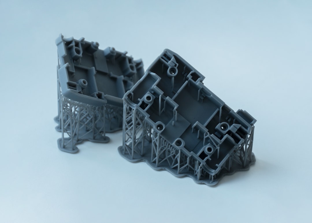 Two gray 3D printed objects with intricate supports